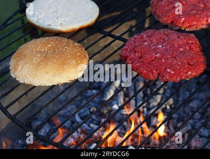 Les burgers de viande et petits pains pour hamburger sur fire grill Banque D'Images