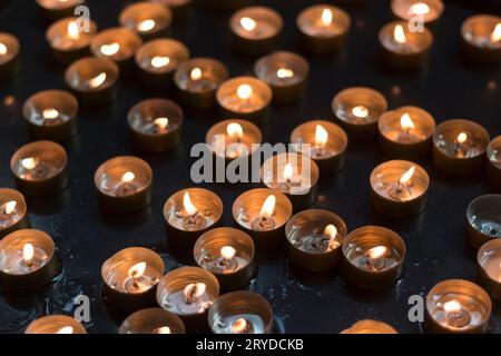 brûlés vers le bas des lumières de thé avec de la cire liquide dans le récipient ainsi que la manière renversée sur la surface noire dans une église chrétienne Banque D'Images