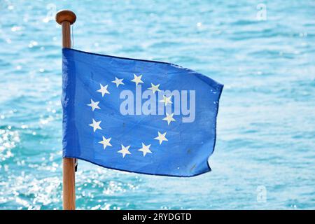 Gros plan drapeau de l'UE ondulant dans le vent au-dessus de l'eau de mer Banque D'Images