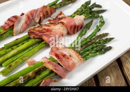 Asperges cuites avec bacon enveloppé sur assiette Banque D'Images