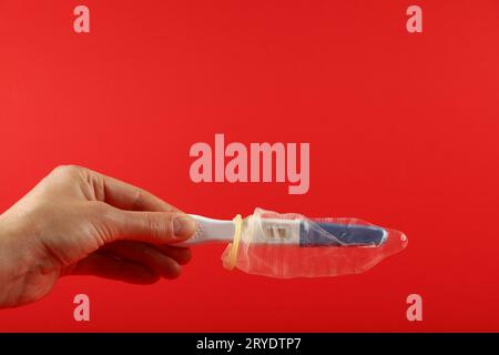Main de femme tenant le test de grossesse avec préservatif Banque D'Images