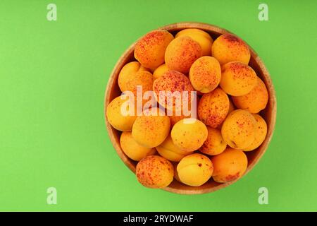 Abricots frais mûrs dans un bol en bois sur vert Banque D'Images