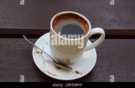 Une tasse blanche de café noir sur une table en bois Banque D'Images