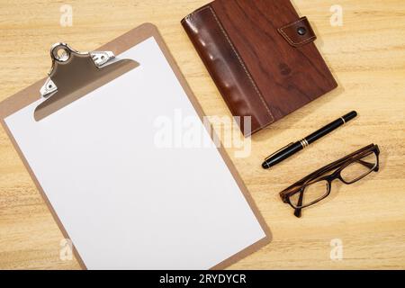 Espace de travail avec clip board vierge, stylo, lunettes et agenda sur la table en bois. Maquette, espace de copie Banque D'Images