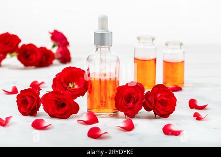 Eau de rose parfumée à la lavande en bouteille en verre et petites roses rouges avec de l'huile de pétales Banque D'Images