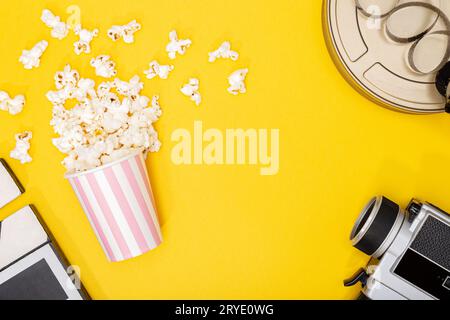 Seau de popcorn, caméra de film, boîte et clapper sur fond jaune Banque D'Images