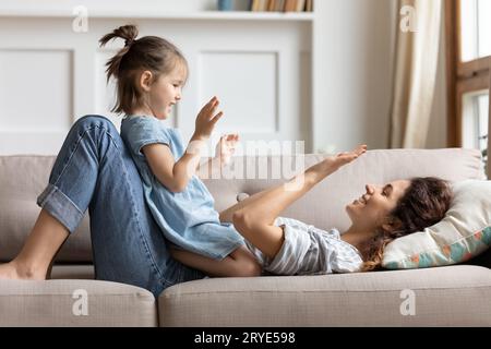 Heureuse jeune maman jouant avec la fille d'enfant d'âge préscolaire à la maison Banque D'Images