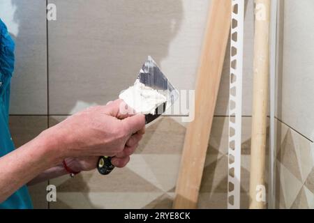 Travailleur avec une spatule en caoutchouc remplir les joints à l'aide d'une solution. Travaux de finition, de troubles de concentration. La technologie de pose de tuile. Banque D'Images