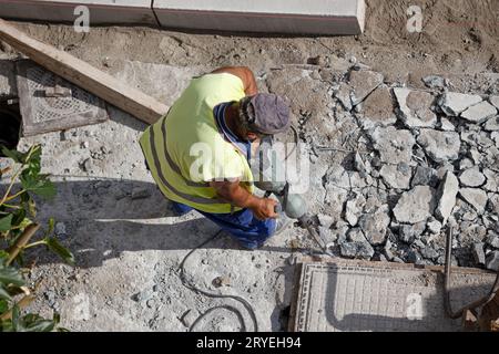 Ouvrier de construction avec marteau perforant le béton sur le trottoir Banque D'Images