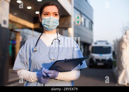 Jeune femme médecin devant l'ambulance des services d'urgence ou l'hôpital Banque D'Images