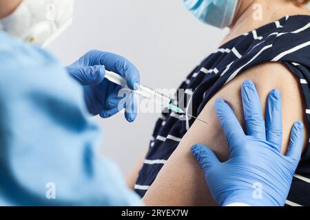 Infirmière administrant la vaccination contre la COVID-19 à un patient volontaire âgé Banque D'Images