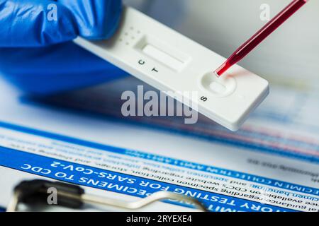 Technicien de laboratoire médical plaçant un échantillon de sang sur un test de diagnostic rapide à l'aide d'une pipette Banque D'Images