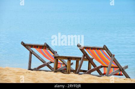 Deux chaises longues en bois colorées sur la plage de sable Banque D'Images