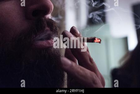 L'homme à la barbe fume une cigarette roulée Banque D'Images