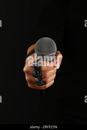 Main homme avec microphone isolé sur noir Banque D'Images