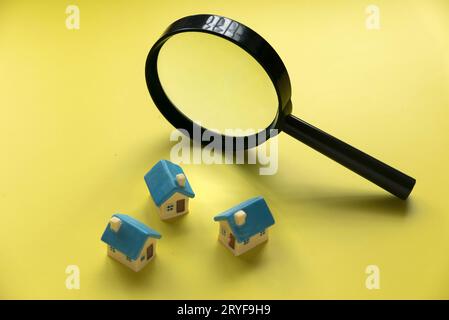 Concept de recherche de maison. Inspection de la maison. Maison miniature avec loupe sur fond jaune. Banque D'Images