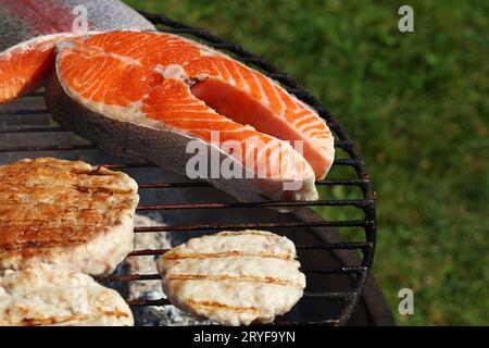 Hamburger de poulet ou de dinde et steak de saumon sur le gril Banque D'Images