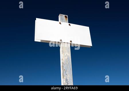 Panneau blanc vierge isolé sur un ciel bleu spectaculaire. Affiche à poteau métallique vieilli. Maquette de modèle Banque D'Images