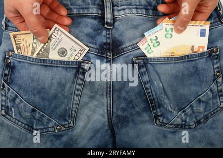 Les mains choisissent les billets de banque dans les poches arrière des jeans Banque D'Images