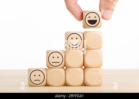 La main choisit le visage souriant sur le bloc de bois. Excellent service aux entreprises évaluant l'expérience client. Concept d'enquête de satisfaction Banque D'Images