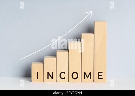 Concept de croissance des revenus. Graphique à barres en bois avec texte et ligne de tendance vers le haut tracée sur fond. Copier l'espace Banque D'Images