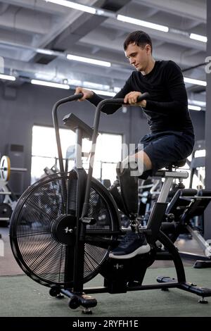 Sportif motivé homme fort sans jambes faisant des exercices cardio sur le vélo. amour de la vie. vue de côté rapprochée Banque D'Images