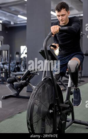 homme actif concentré sur l'entraînement sur un vélo stationnaire. Un homme fait du sport dans la salle de gym. tir en longueur. motivation, entraînement en force Banque D'Images