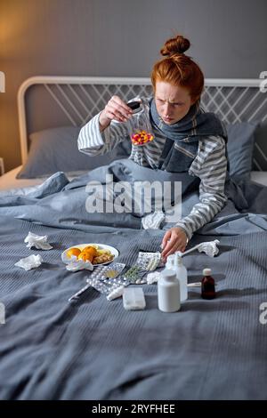 femme en colère frustrée tenant une bouteille avec des vitamines colorées, les regardant avec une expression douteuse, elle ne croit pas qu'elle ira bien ainsi Banque D'Images