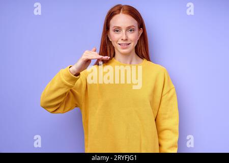 Femme caucasienne joyeuse avec de longs cheveux rouges montrant la lettre F. symbole de langue des signes pour l'homme sourd dans le fond bleu. isolé Banque D'Images