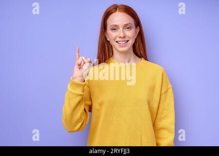 Belle rousse heureuse fille joyeuse, professeur montrant la lettre J sur fond bleu. Alphabet de langue des signes. éducation gratuite pour les enfants sourds Banque D'Images