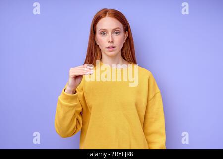 Belle rousse fille sérieuse, professeur montrant la lettre T sur fond bleu. Alphabet de langue des signes. éducation gratuite pour les enfants sourds Banque D'Images