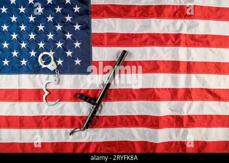 Menottes en métal argenté et bâton de nuit de police sur le drapeau américain sur une surface plane Banque D'Images