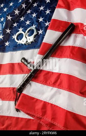 Menottes en métal argenté et bâton de nuit de police sur le drapeau américain sur une surface plane Banque D'Images
