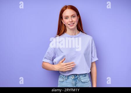 joyeuse rousse touchant son ventre, montrant qu'elle est pleine, gros plan portrait isolé fond bleu Banque D'Images