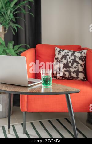 Fauteuil confortable, ordinateur portable et un verre de boisson. Banque D'Images