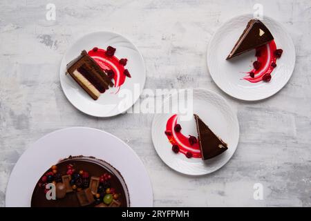 Plan du dessus de délicieux morceaux de gâteau au chocolat servis avec une sauce aux baies sur des assiettes. Banque D'Images