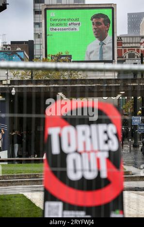 Manchester, Royaume-Uni. 30 septembre 2023. Un panneau indiquant « Tories out » est bien visible lors d'une réunion pour discuter de la paix dans le monde dans la tente de l'Assemblée du peuple à Piccadilly Gardens tandis qu'un panneau d'affichage au-delà montre le Premier ministre Rishi Sunak. L'événement a été organisé pour protester contre les politiques du gouvernement lors de la conférence du Parti conservateur. Crédit : SOPA Images Limited/Alamy Live News Banque D'Images