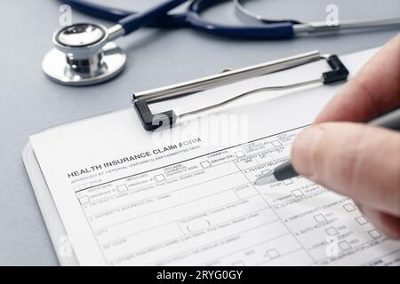 Remplir manuellement le formulaire de demande d'assurance maladie et le stéthoscope sur le bureau Banque D'Images
