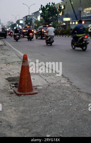 Un barrage orange à côté de la route, un panneau pour quelques nids de poule sur la route. Banque D'Images