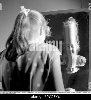 Parc d'attractions Gröna Lund dans les années 1950 Une adolescente se promène dans la salle de rire. Une maison de miroirs dans laquelle vous pouvez vous promener et réfléchir. Selon le type de miroir dans lequel vous regardez, vous pouvez être grand ou court, gras ou mince. L'explication est que les miroirs sont soit concaves, soit convexes, soit une combinaison des deux. 31 mai 1958. Conard réf. 3760 Banque D'Images