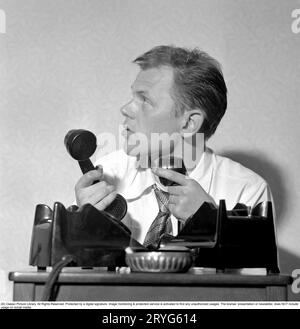 Dans les années 1950 Sixten Larsson avec deux téléphones qui semblent occupés lorsqu'ils tiennent deux combinés. Suède 1952. Conard réf. 2020 Banque D'Images