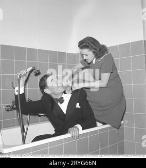 ODD dans les années 1940 Sture Lagerwall, 1908-1964. Acteur suédois ici avec l'actrice Sonja Wigert, qui sont tous les deux vus entièrement vêtus dans une baignoire. Il tient la douche sur lui sans éclabousser d'eau sur lui-même et la femme le lave de manière ludique avec une brosse. Suède 1945. Kristoffersson R47-6 Banque D'Images