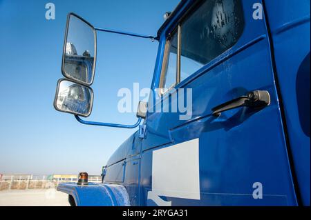 Gros plan d'une porte bleue de camion à benne basculante avec rétroviseur sur un chantier de construction Banque D'Images