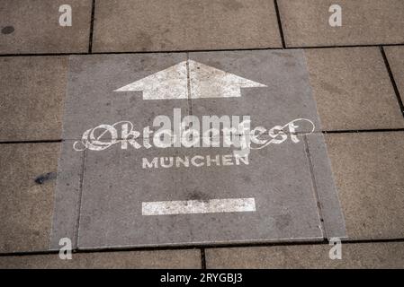 Munich, Allemagne-30 septembre 2023 : panneau peint sur le trottoir indique la direction vers le terrain de l'oktoberfest. Banque D'Images