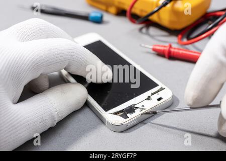 Mains du technicien travaillant sur le smartphone cassé pour réparer ou remplacer une nouvelle pièce sur le bureau Banque D'Images