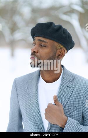 Jeune homme en béret comme Che Guevara rester sur fond d'hiver. Veste de maintien afro-américaine regardant de côté. Banque D'Images