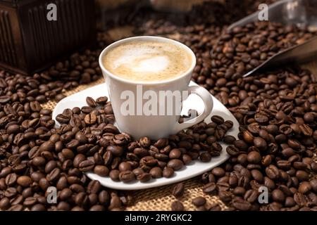 Cappuccino ou café avec tasse de lait et grains torréfiés sur la table Banque D'Images