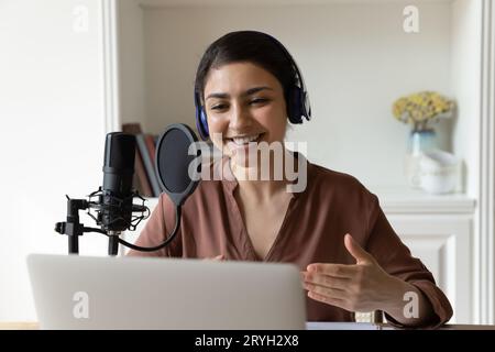 Tête prise de vue souriante femme indienne dans un casque à l'aide d'un microphone professionnel Banque D'Images