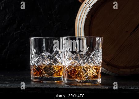 Whisky dans des verres avec un tonneau. Whisky Bourbon et fût sur fond sombre Banque D'Images