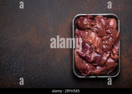 Foie de poulet cru dans le plateau de supermarché noir vue de dessus sur la table de cuisine de fond en béton rustique foncé. Ingrédient alimentaire sain, Banque D'Images